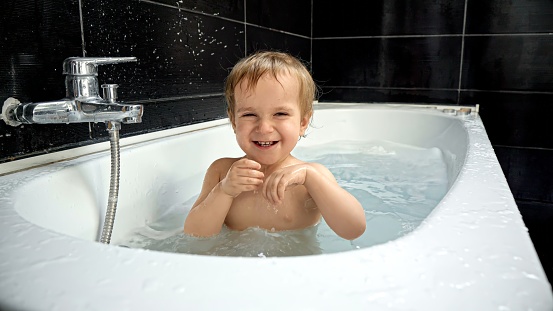Baby boy's excitement during bath time, as he kicks and splashes with pure joy, creating ripples in the water
