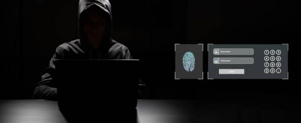 istock Professional hacker with laptop and mobile phone sitting at table on dark background 1627192437
