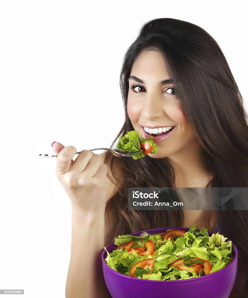 Woman eating salad Picture of pretty woman eating green salad, closeup portrait of brunette female holding bowl with fresh vegetables isolated on white background, healthy lifestyle, organic nutrition, dieting concept Adult Stock Photo