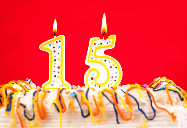 Decorated birthday cake with number 15 burning candles. Red background.