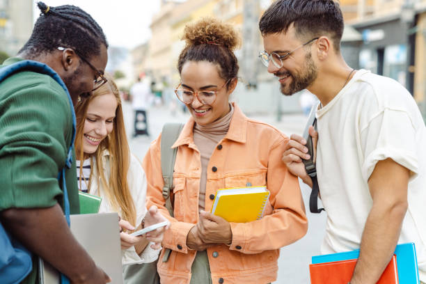 istock Cheerful students using smart phone on the street 1627214410