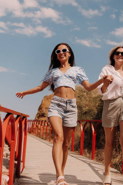 istock Two beautiful young women holding hands and smiling while running outdoors together 1627217085