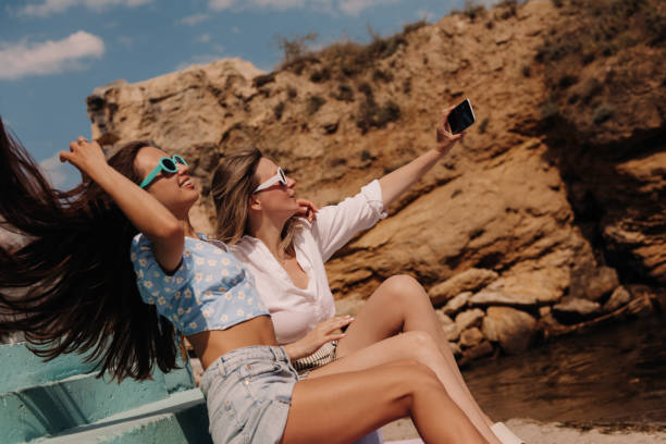 istock Two attractive young women making selfie and smiling while sitting outdoors together 1627219784