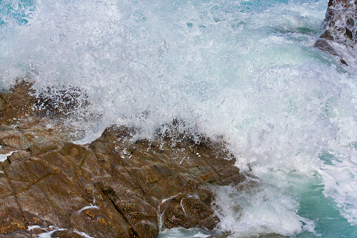 Breaking wave in rocky coastline. Splashing droplets. Foz, A Mariña area, Lugo province, Galicia, Spain.