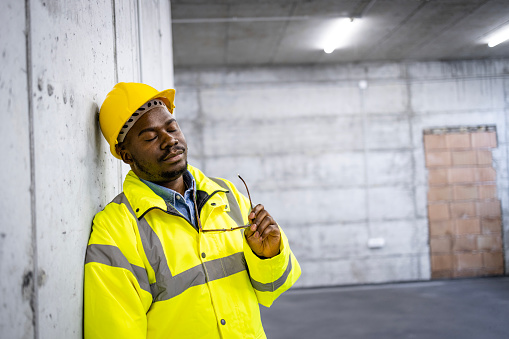 Construction worker sleeping at construction site during work time due to tiredness.