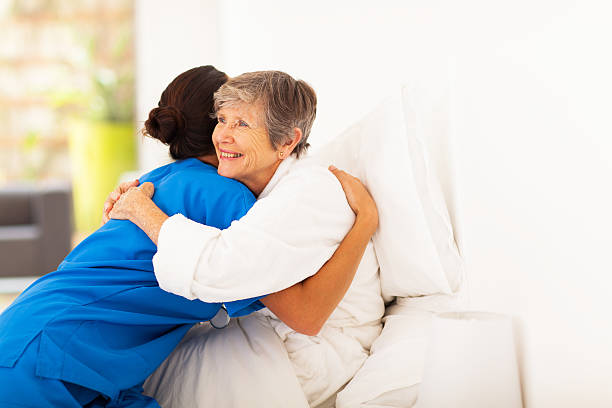 ältere frau umarmen fürsorgliche auf bett - community outreach home caregiver care cheerful stock-fotos und bilder