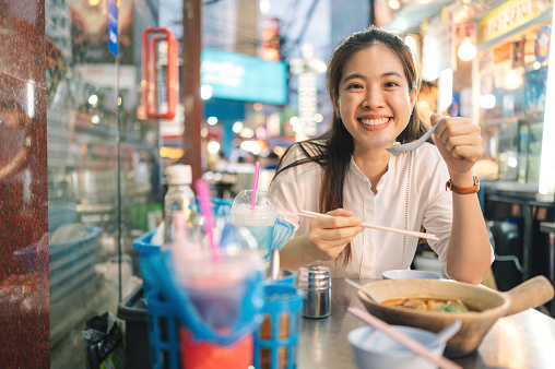 Attractive travel asian eat-in sitting on the streetside eat Stir-Fried Rice Noodle with Fish Maw and Crab  street food at china town yaowarat bangkok thailand