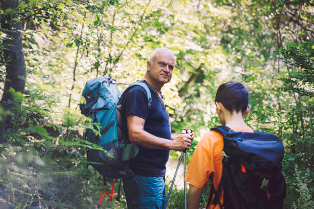 Grandfather and grandson hiking trough forest. Sustainability stock photo