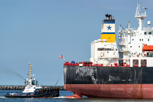 Technician standing on passenger ship deck and preparing for transfer on big transfer vessel. Offshore platform behind.