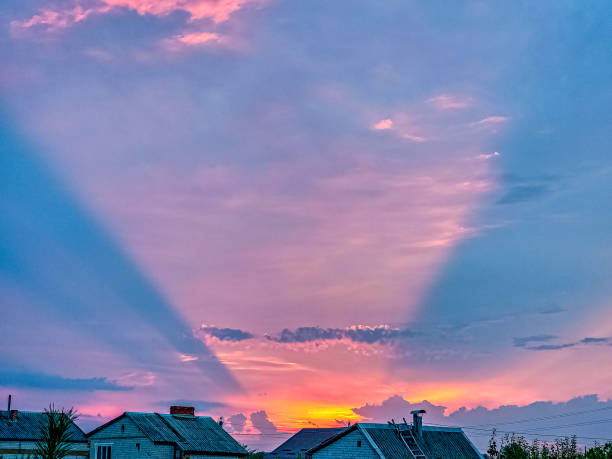 Unusual sunset. Pink conical optical effect from the rays of the setting sun in the clouds.