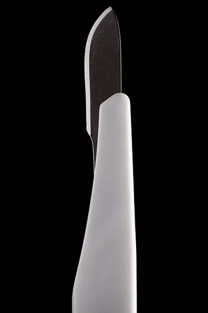 Detail of the blade of a surgical disposable scalpel (number 10) , isolated on a black background