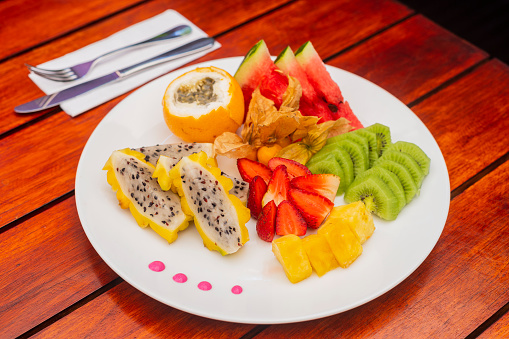 Healthy fruit breakfast on the hotel table based on strawberries, pineapple, dragon fruit, granadilla