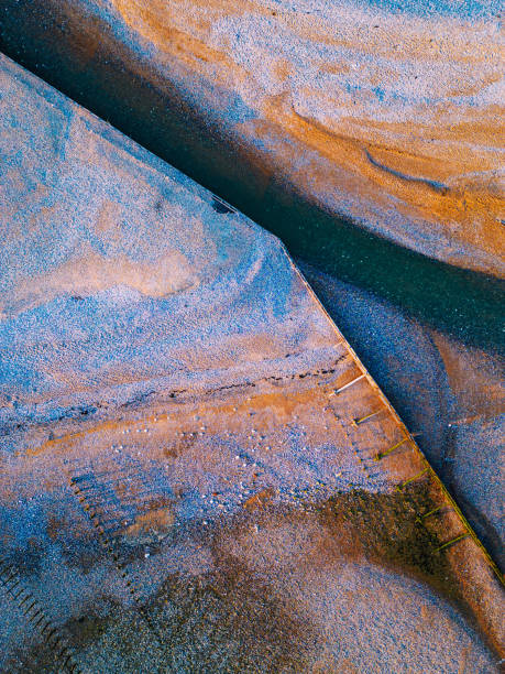 istock Abstract aerial topdown view of shapes and patterns on pebble beach at sunset 1627308477