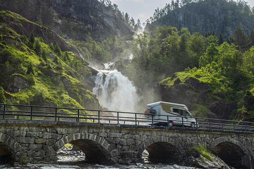 Holiday trip in motorhome, Caravan car Vacation. RV traveling on the road Latefossen Waterfall Odda Norway. Latefoss is a powerful, twin waterfall.