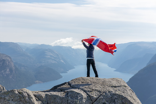 Woman with a waving flag of Norway on the background of nature