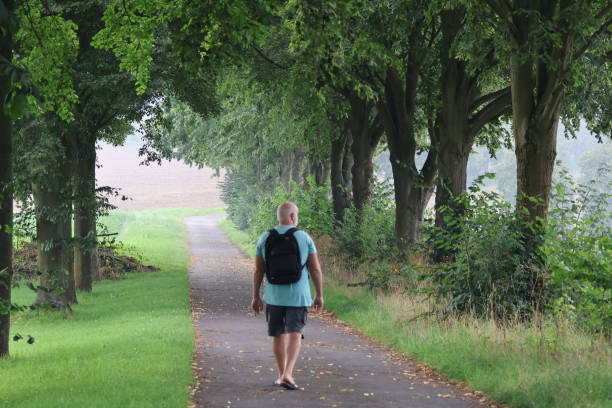 istock mature gray-bearded man with a backpack enjoys a morning walk 1627319261