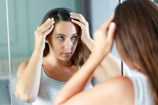 istock Young woman looking in mirror and having problem with hair loss 1627329236