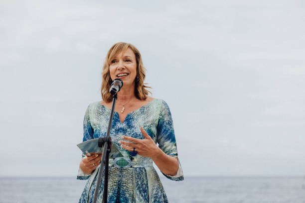 senior woman gives speech above sea - foton med speaker bildbanksfoton och bilder