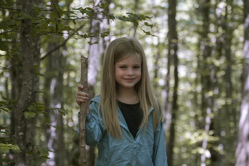 Adorable little girl hiking in the forest, spending time in the nature, outdoors experience in the countryside