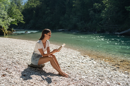 She reads book on riverbank