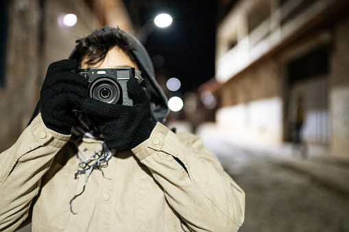 Portrait of boy taking photo on the street in winter