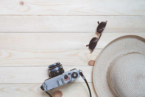 Top view travel accessories on wood texture background. Blogger journey with camera film, hat, sunglasses in summer concept.