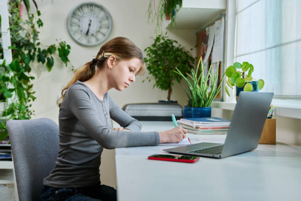istock Preteen girl studying at home, using laptop computer 1627367529