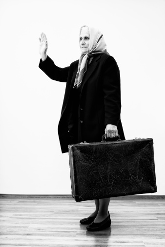 Senior woman with suitcase waving