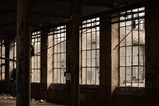 The picture of barred broken windows and rusty pillars in the interior of an abandoned building