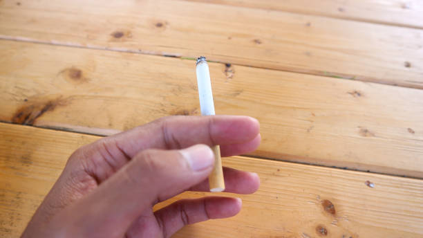 istock hand holding cigarette and smoke on wooden background 1627468758