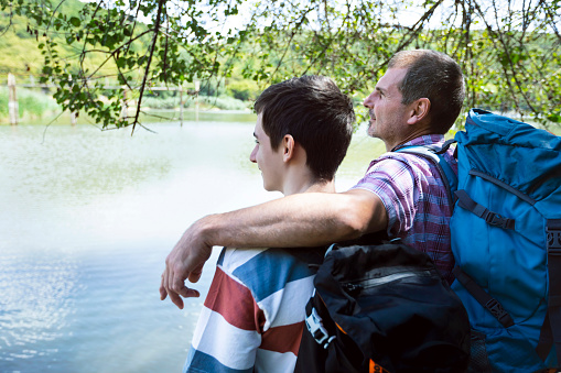 Back view of father and son enjoying а lake and beautiful nature.