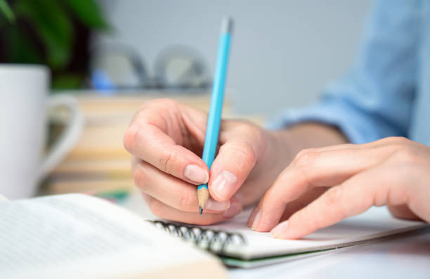 istock A young girl student prepares her homework and writes notes in a notebook. Close-up. Selective focus. 1627533686