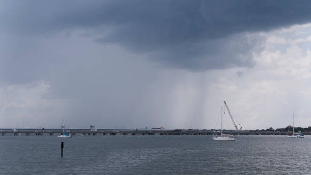 o clima extremo ameaçador começa acima do canteiro de obras da ponte. skyline de phoebus ao longe, hampton roads, va. - sailboat pier bridge storm - fotografias e filmes do acervo