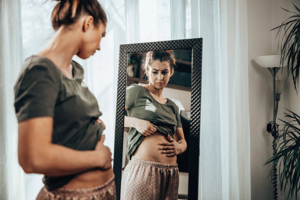 mujer que sufre de calambres estomacales - dieting mirror healthy lifestyle women fotografías e imágenes de stock