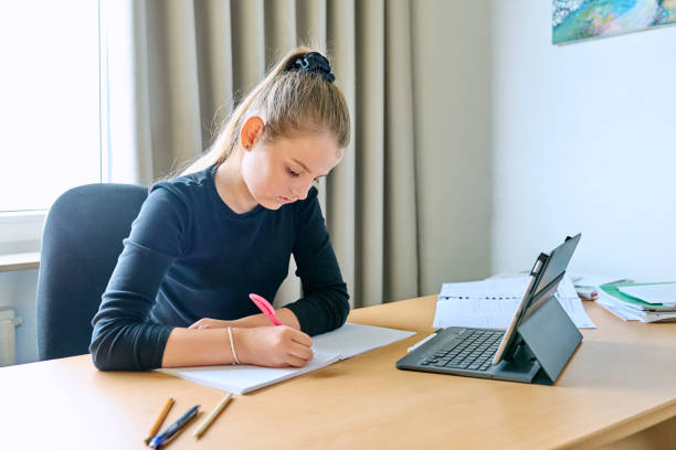 istock Girl child studying at home, sitting at her desk using digital tablet 1627577838