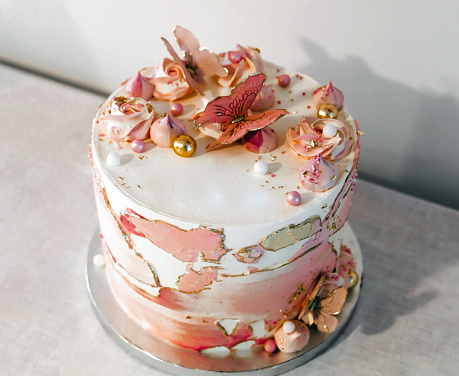 Birthday cake decorated with pink sugar flowers and butterflies.