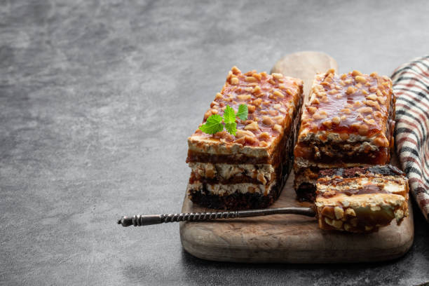 Layered cake with caramel cream and nuts on gray background