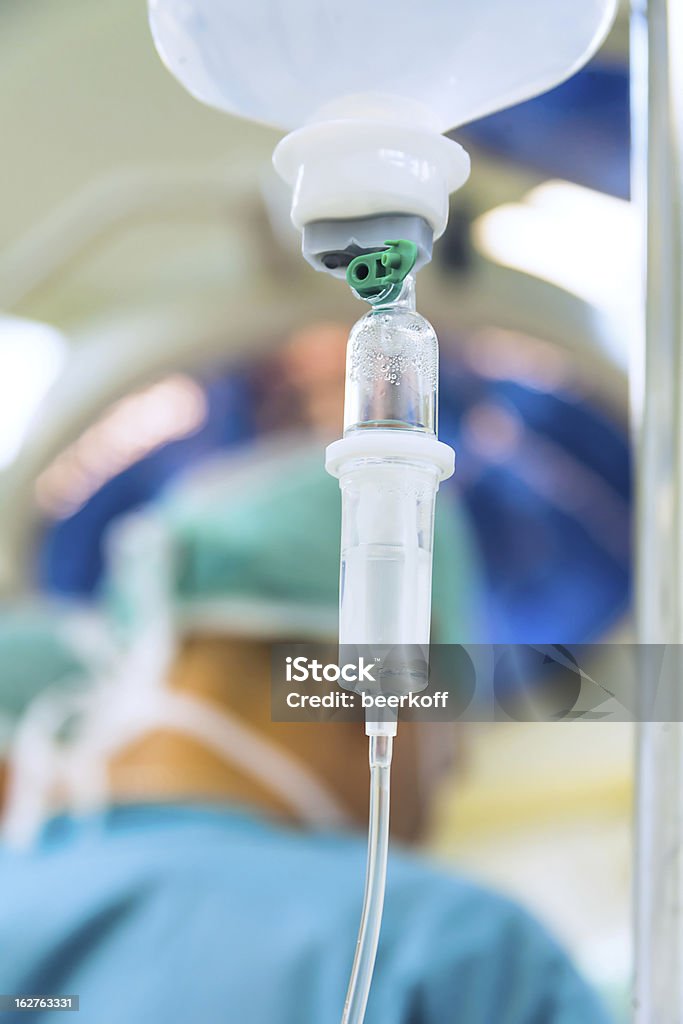 Perfusion intraveineuse avec chirurgien en arrière-plan - Photo de Bouteille libre de droits