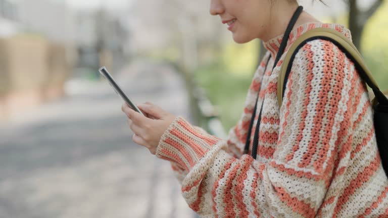 Side view asian female tourist using smartphone to text with her family while travel in Japan.