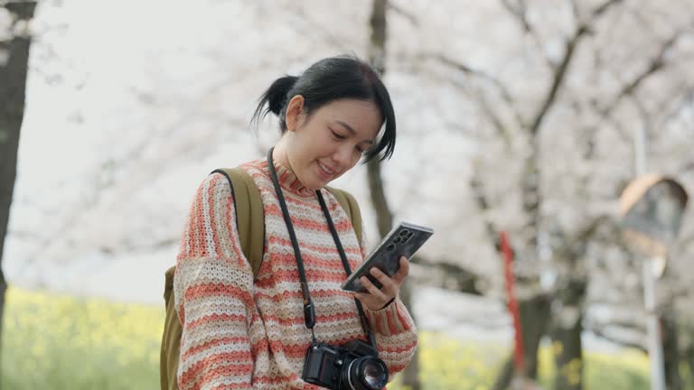 Happy asian woman using smartphone to text with her boyfriend while holiday travel in japan.