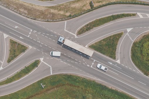 Aerial shot of large semi-truck, a van and a pickup truck on road intersection from drone pov, directly above