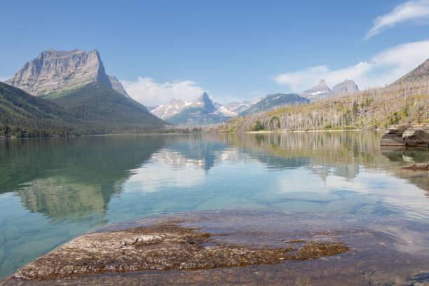 istock the mountains reflected in water are visible from a rocky shore 1627674792