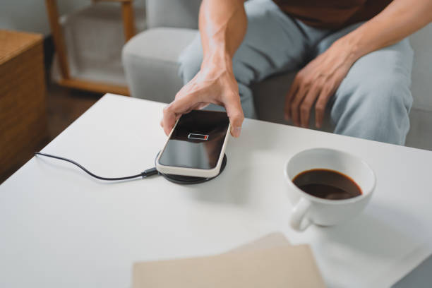 istock Man hands plugging a charger in a smart phone. Charging Smartphone with Wireless Charging Pad at Home 1627709934