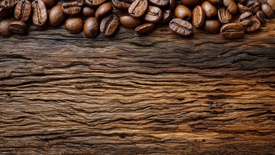 A close up shot of freshly roasted coffee beans spread out on a wooden table