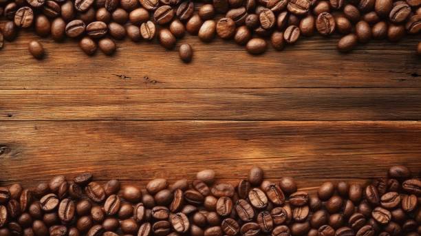 istock coffee beans are scattered over a wooden table with space for text 1627745215
