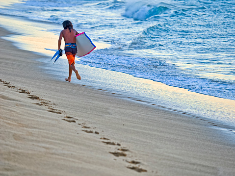 The Pacific Island of Maui in Hawaii on January  11, 2023:  Young adult boogie boarding off of the Kaanapali Beach in Maui