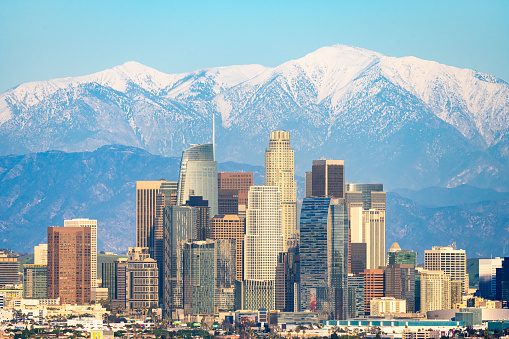 Skyline of Los Angeles with snow-capped mountain in background.