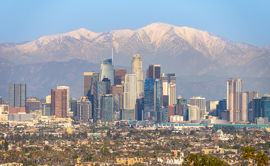 Skyline of Los Angeles with snow-capped mountain in background.