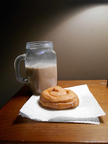 Glass of chocolate milk and a honey bun.