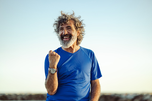 Portrait of a senior man at the beach on a sunny afternoon looking away. Proud and satisfied old man in casual enjoying summer holiday at the beach